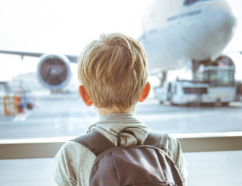 child looking through window at airplane