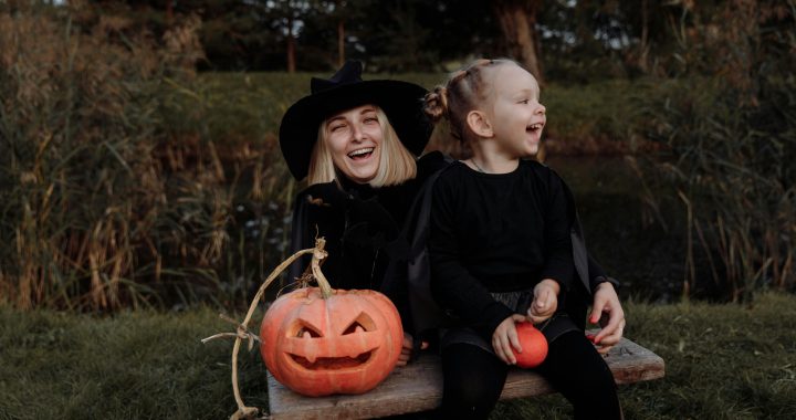 Witch Mom and Daughter on Halloween with a carved Pumpkin